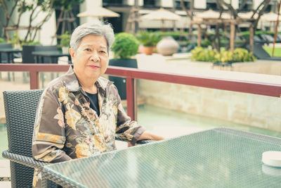 Elder woman resting relaxing on balcony terrace at hotel resort. elderly senior leisure lifestyle