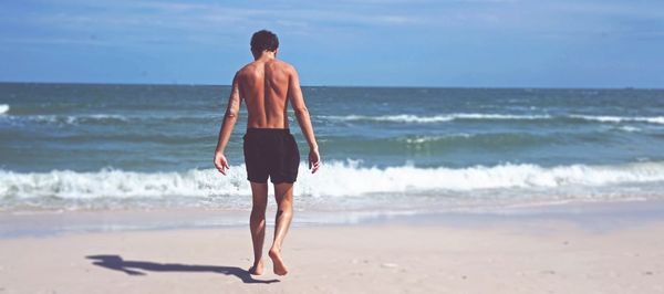 Rear view of shirtless man standing on beach