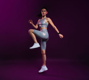 Full length of woman exercising against black background