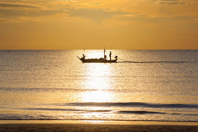 Silhouette people in sea against sky during sunset