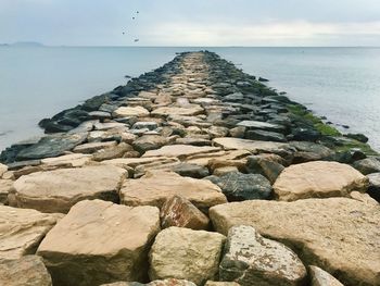 Stone wall by sea against sky