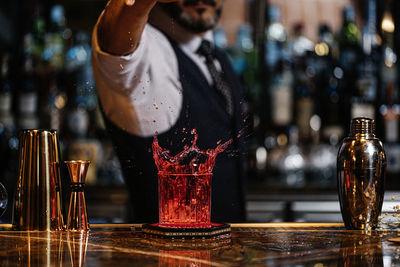 Reflection of man in glass bottle on table