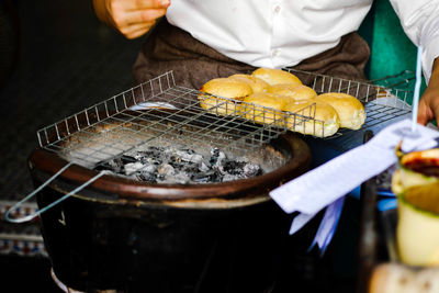 Close-up of person preparing food on barbecue grill