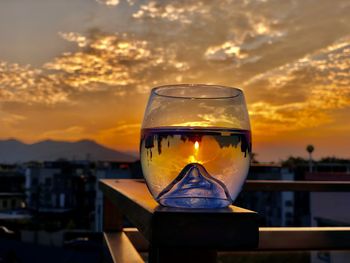 Close-up of wineglass against sky during sunset