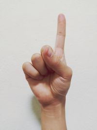 Cropped hand of person pointing against wall