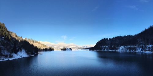 Scenic view of lake amidst mountains against blue sky