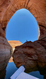 Rock formation over lake against clear blue sky
