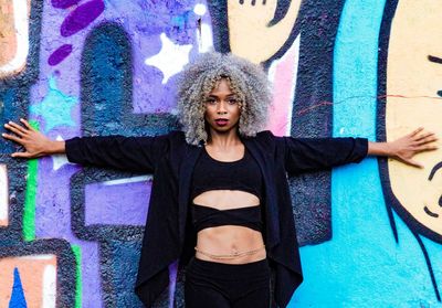 Portrait of beautiful young woman standing against graffiti wall