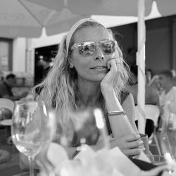 Portrait of woman wearing sunglasses with glass on table