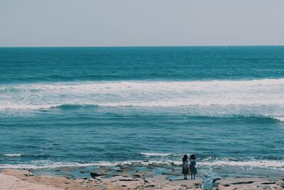 Rear view of women standing at seashore