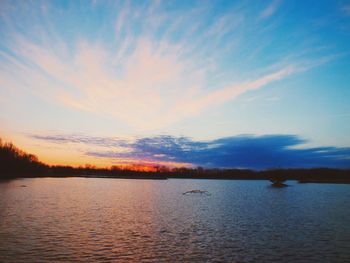 Scenic view of lake against sky at sunset