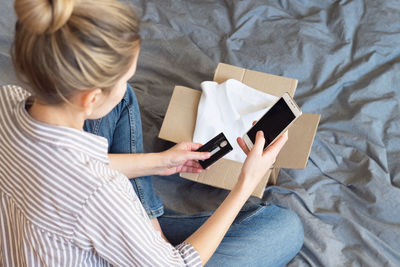 High angle view of woman using mobile phone while sitting on bed