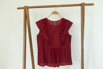 Red colour blouse is clothes hanger on white background.