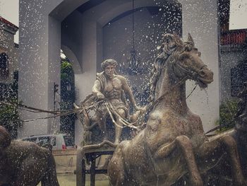 Statue by glass building in city