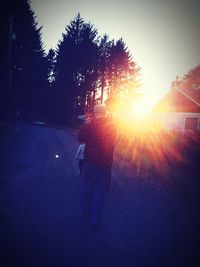 Rear view of people walking on street against sky during sunset