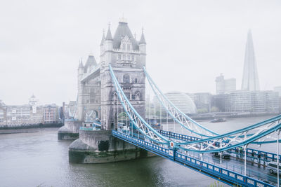 Tower bridge over river against buildings in city