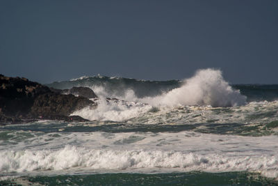 Waves splashing on sea against mountain