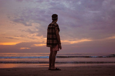 Man standing on beach against sky during sunset