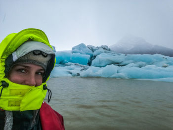 Portrait of woman wearing warm clothing against sea during winter