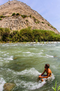 Man sitting on rock in river