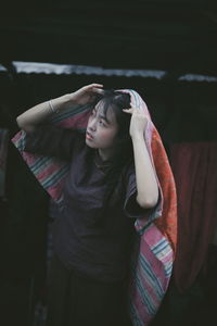 Young woman covering head with blanket while standing outdoors