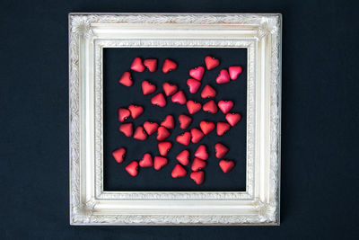Directly above shot of red heart shapes in picture frame on black background