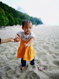 Cropped parent holding hand of baby girl at beach