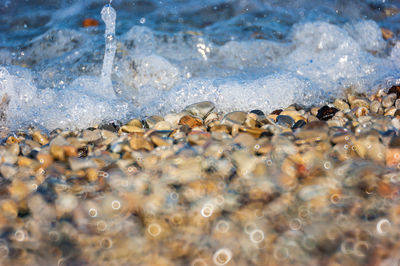 Sea waves crashing on a beach of colored stones