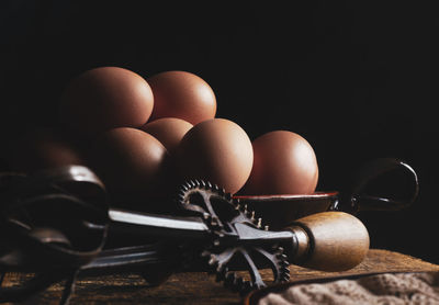 Organic chicken eggs on wood with a iron whisk, dark backround