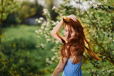 Young woman standing against trees