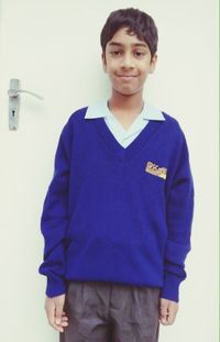 Portrait of smiling boy standing against wall