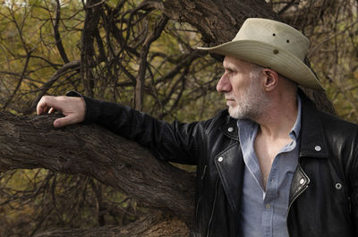 Portrait of adult man in cowboy hat against tree