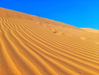 Scenic view of desert against clear blue sky