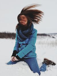 Full length of smiling young woman on beach during winter