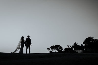 Rear view of couple walking against clear sky