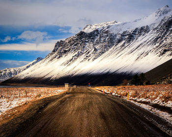 Road amidst snowcapped mountains against sky