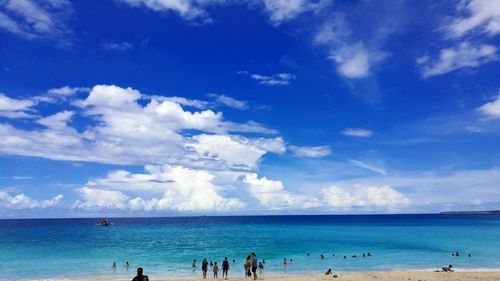 People on beach against blue sky