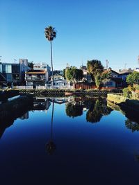 Reflection of houses and trees against clear blue sky