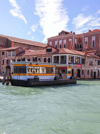 Boats in canal by buildings against sky in city