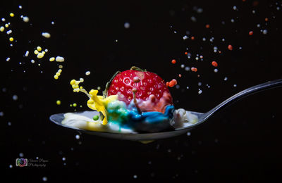 Close-up of multi colored candies in container against black background