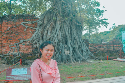 Portrait of smiling young woman against trees