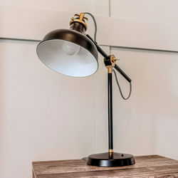 Close-up of electric lamp on table against wall