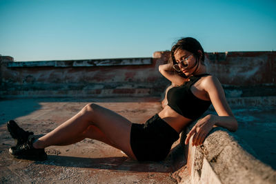 Young woman sitting on sofa against sky