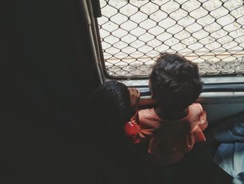 High angle view of children looking through window in train