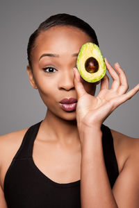 Close-up portrait of young woman holding fruit