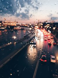 Cars on road seen through wet glass window