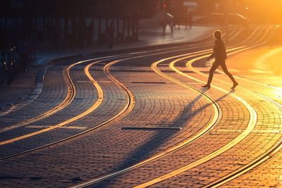 Side view of silhouette woman crossing city street during sunset