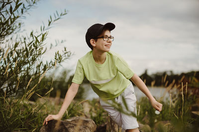 Boy having fun on rocks while climbing on hard stone shore and discovering new things