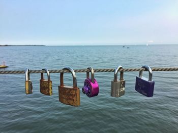 Close-up of padlocks on railing against sea