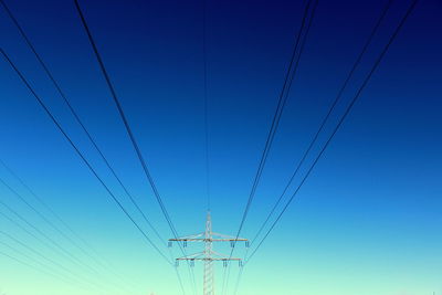 Low angle view of electricity pylon against blue sky